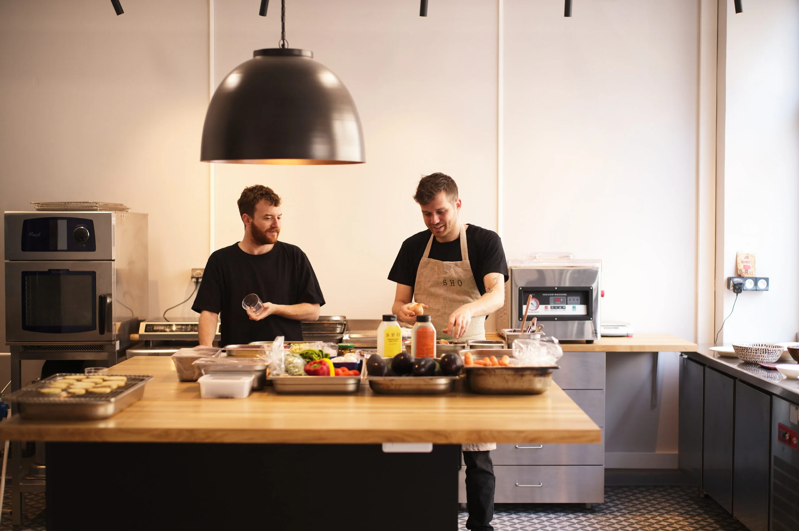 Équipe EATTT préparant des légumes frais dans une cuisine professionnelle avec des bouteilles de stock SHO sur le plan de travail