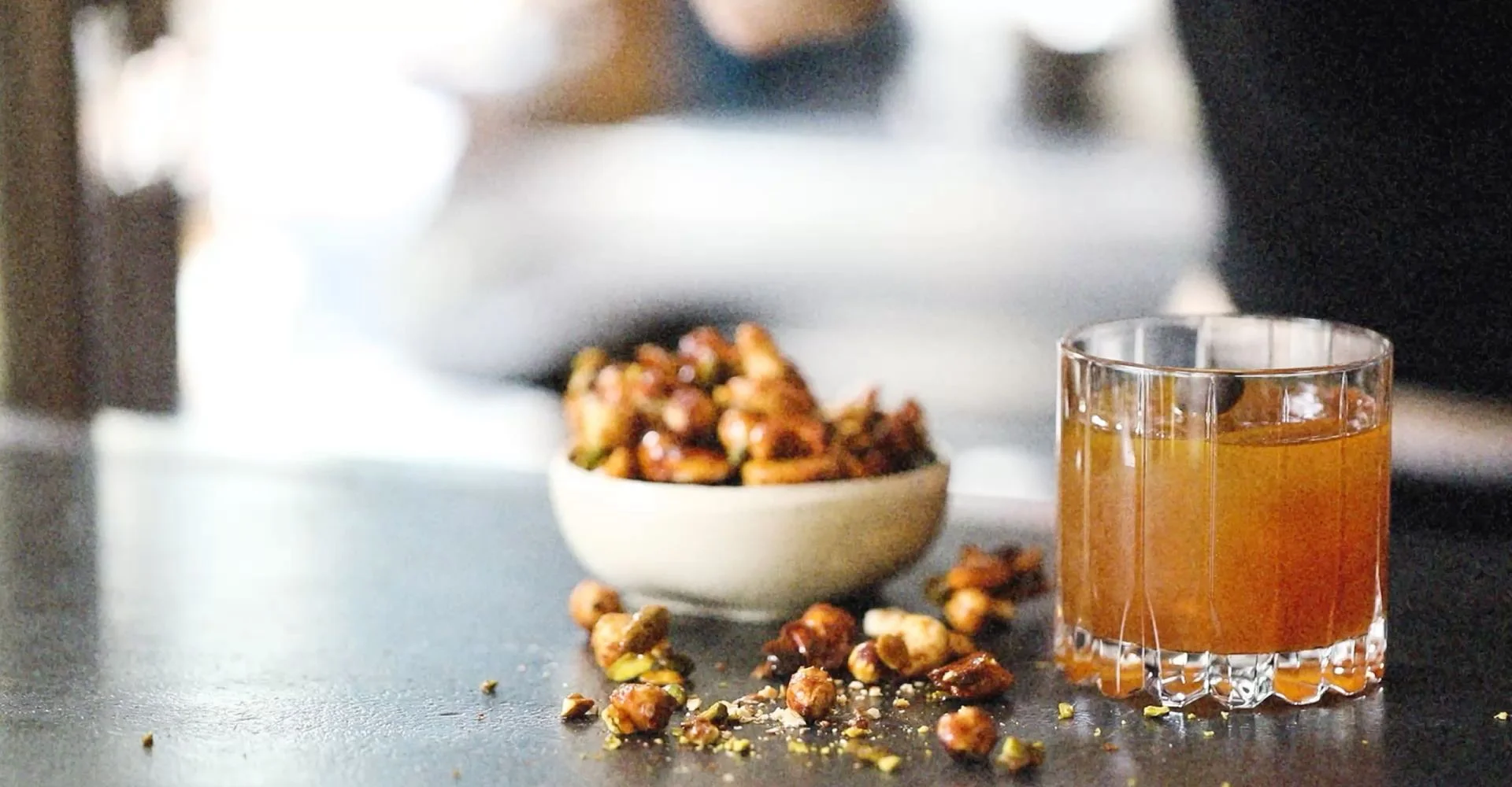 Bol de noix caramélisées et un verre de boisson ambrée, bannière de la page SHO Umami Booster