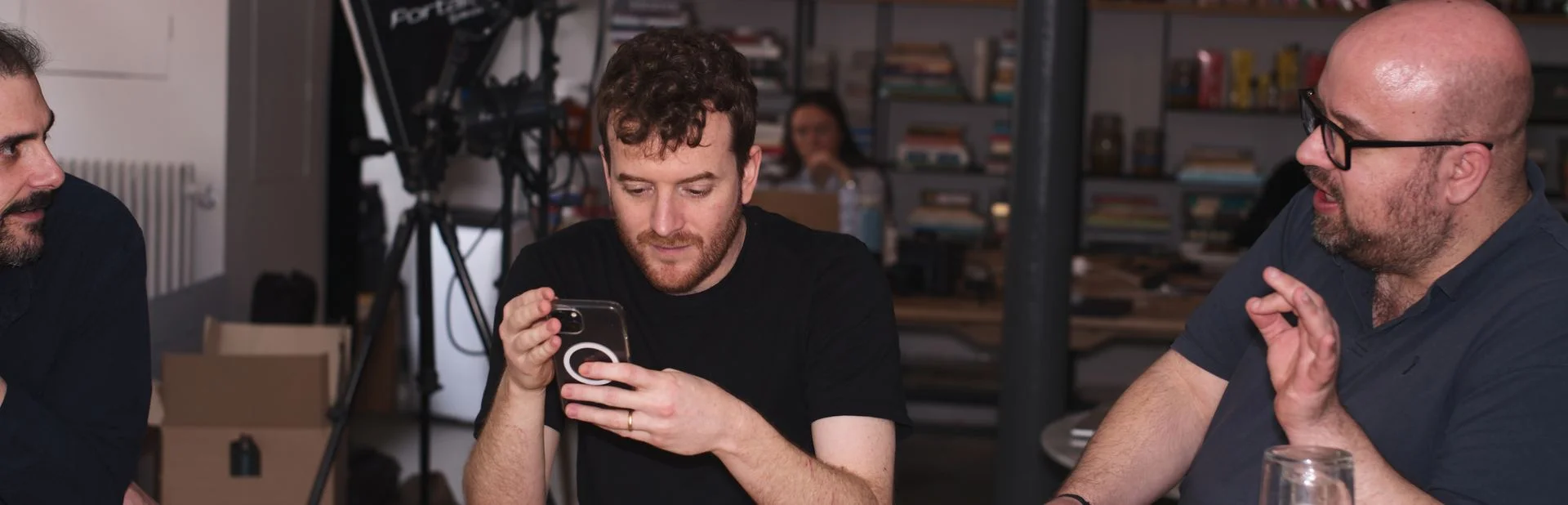 EATTT team members in a studio setting, one checking content on a phone, banner for the Contact page