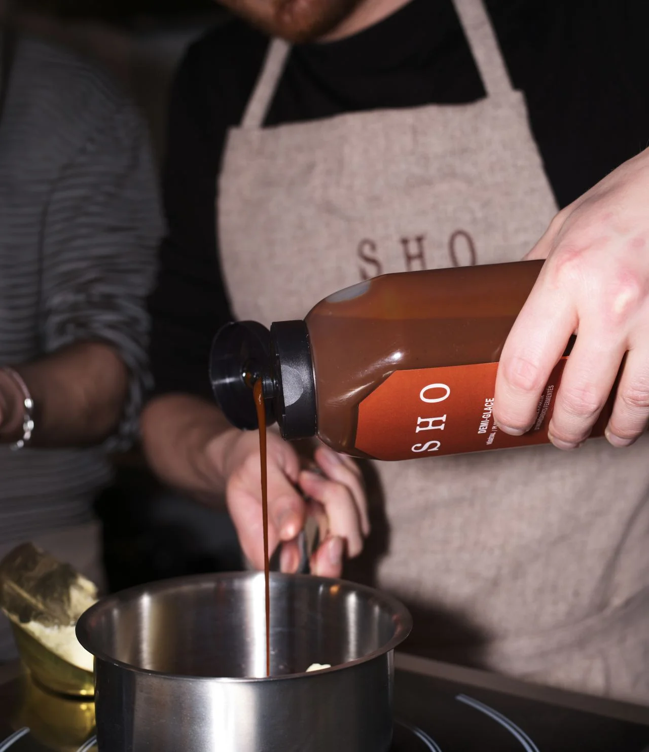 Chef versant du concentré SHO demi-glace dans une casserole en métal pendant la cuisson