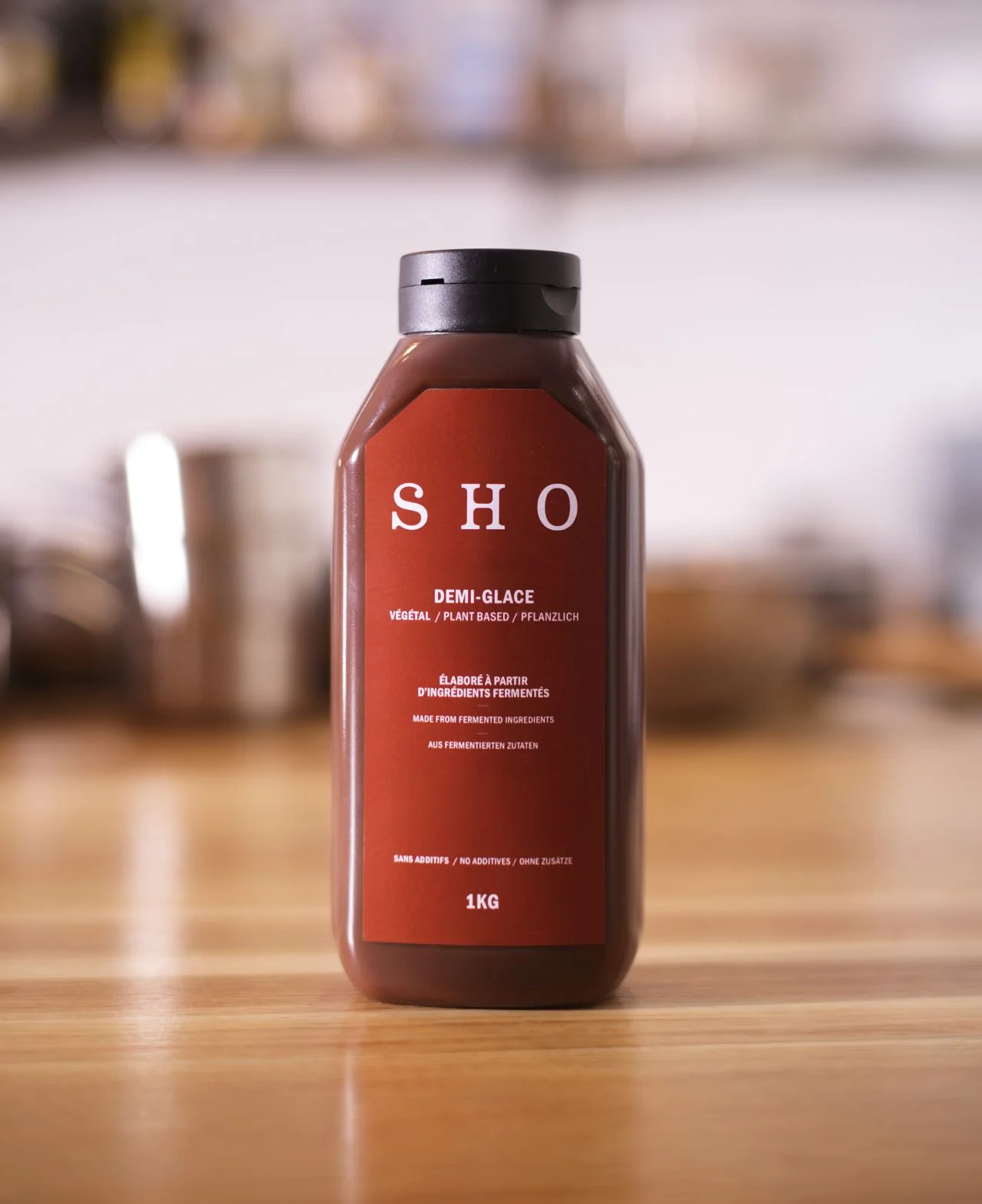 Bouteille de demi-glace SHO sur un comptoir en bois, une sauce végétale à base de café, sarrasin et pois chiches fermentés