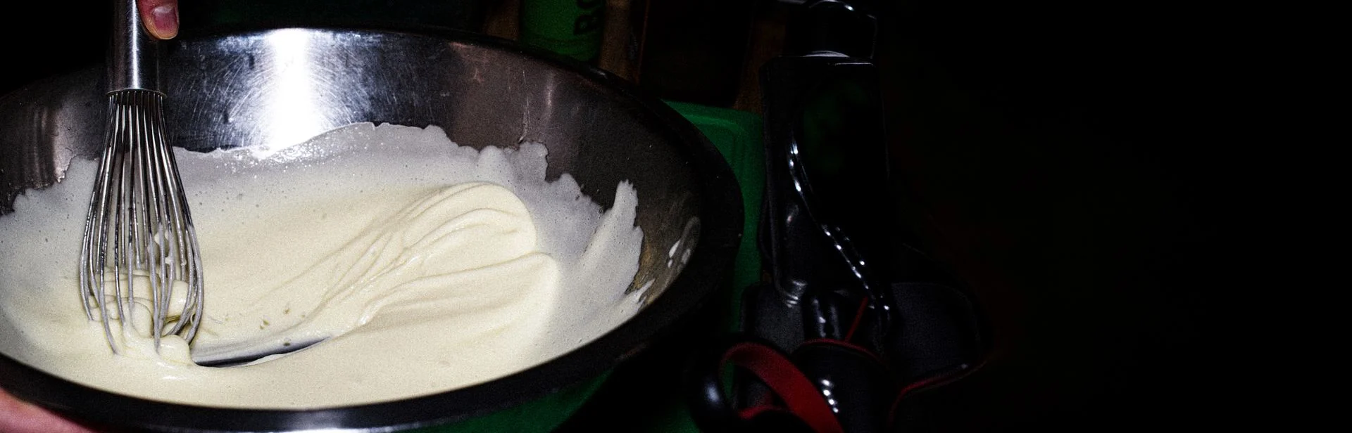 Whisk mixing a creamy white sauce in a metal bowl with an Alain Chapel quote about eating the truth