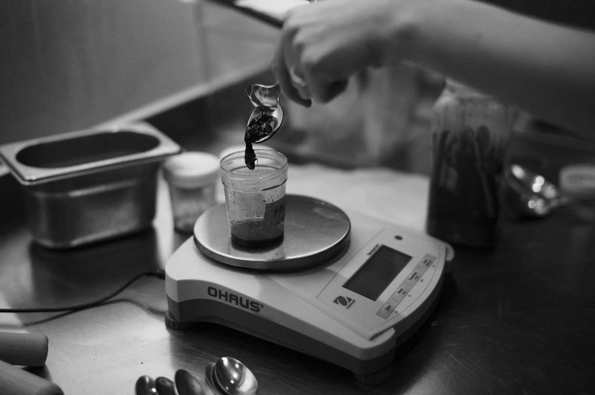 Photo en noir et blanc d'un échantillon de saveur pesé sur une balance de laboratoire, illustrant le problème d'opacité dans l'alimentation